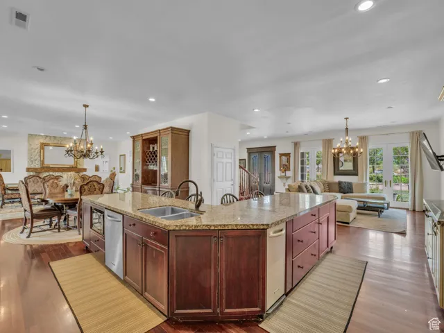 Kitchen featuring a chandelier, open floor plan, a center island with sink, hard wood  floors, and recessed lighting