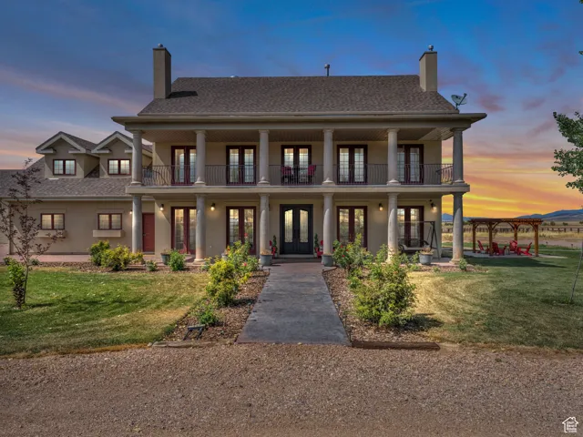 View of front of home featuring french doors, a chimney, a lawn, and stucco siding