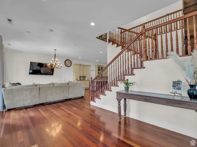 Living room with hardwood floors, stairs, recessed lighting, and a chandelier