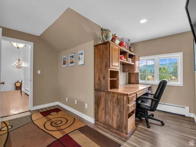 Office area with wood finished floors, recessed lighting, vaulted ceiling, baseboard heating, and a chandelier