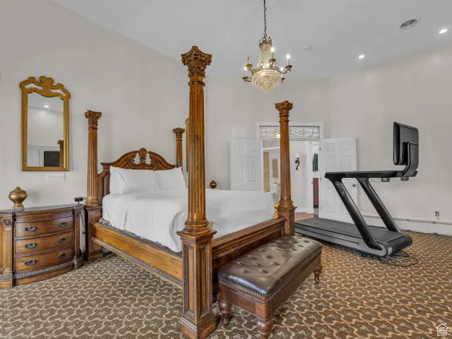 Carpeted bedroom with a chandelier and recessed lighting
