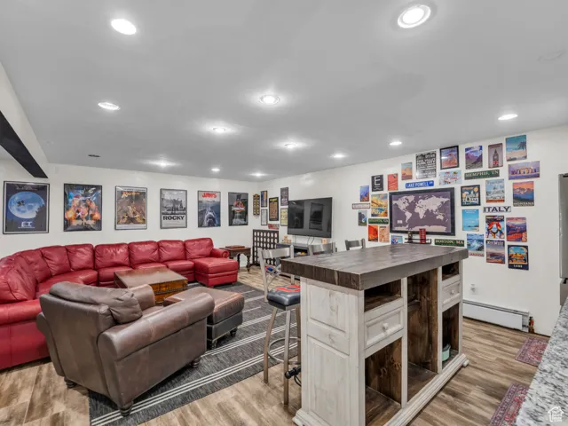 Living room with baseboard heating, light wood-style flooring, and recessed lighting