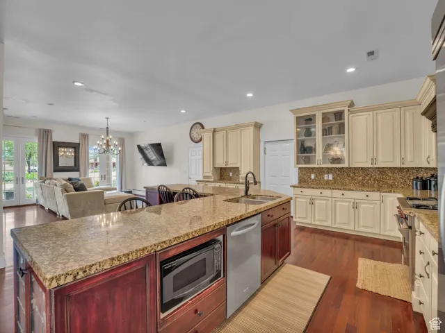 Kitchen featuring cream cabinetry, an island with sink, appliances with stainless steel finishes, backsplash, and recessed lighting
