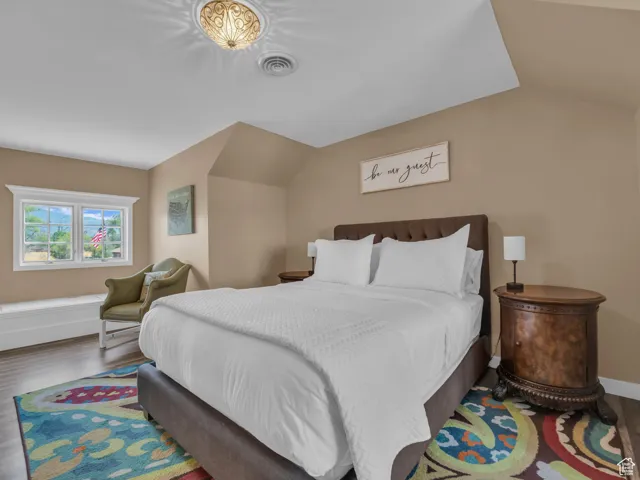Bedroom with wood finished floors and vaulted ceiling
