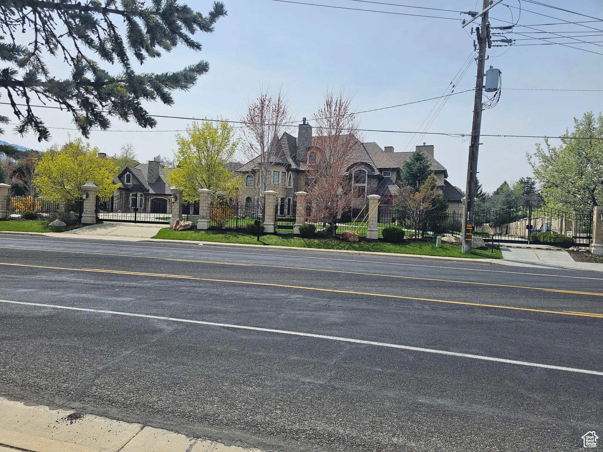 View of asphalt road with curbs, a gate, and sidewalks