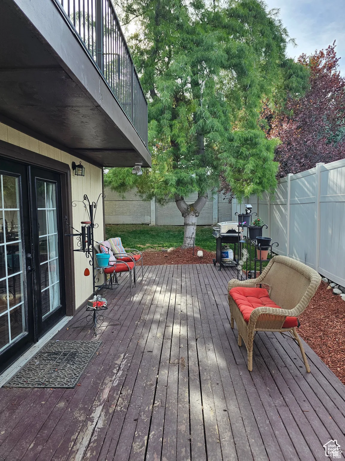 Wooden terrace with a fenced backyard and french doors