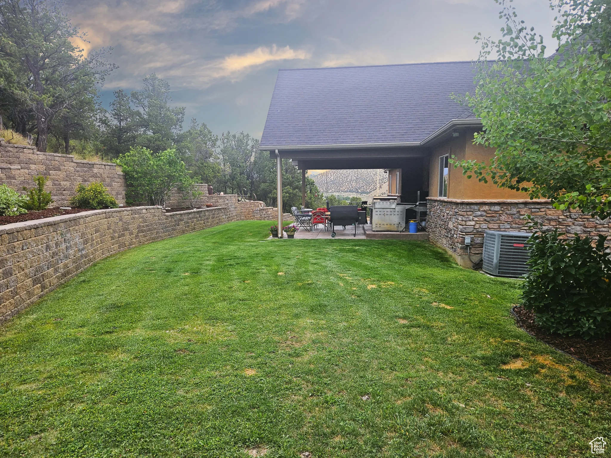A sprawling yard unfolds around the home, with natural contours, mature trees, and open grassy spaces that invite exploration and relaxation.