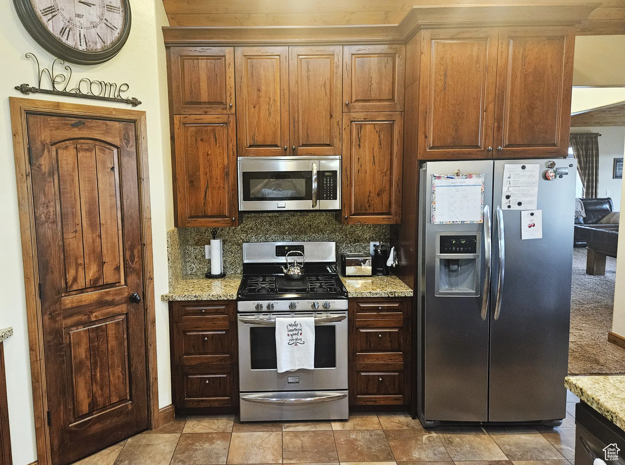 Stainless steel appliances add a polished touch while complementing the warm wood cabinetry and natural stone counters.