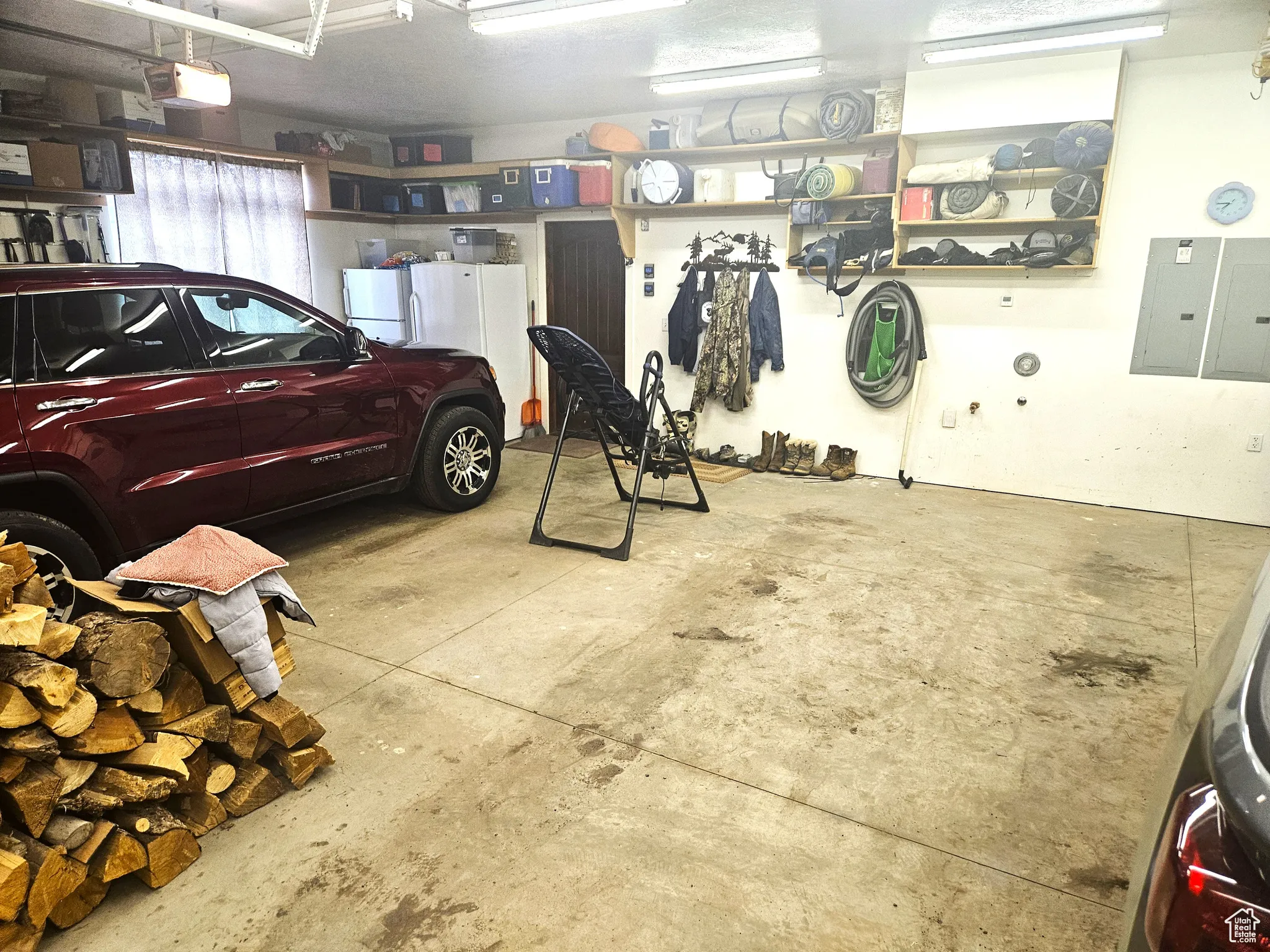Garage featuring electric panel, freestanding refrigerator, and a garage door opener