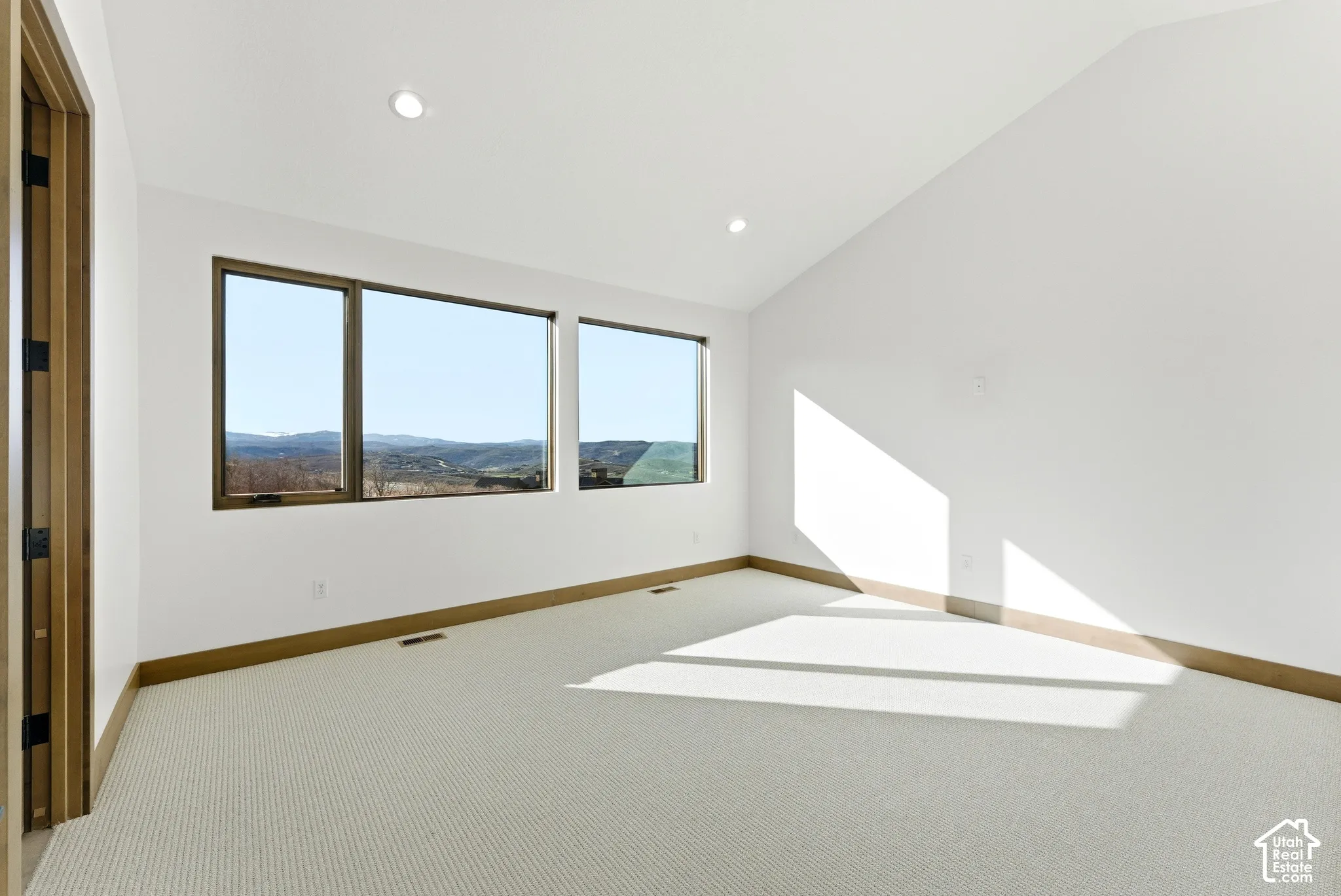 Unfurnished room with light colored carpet, lofted ceiling, and a mountain view