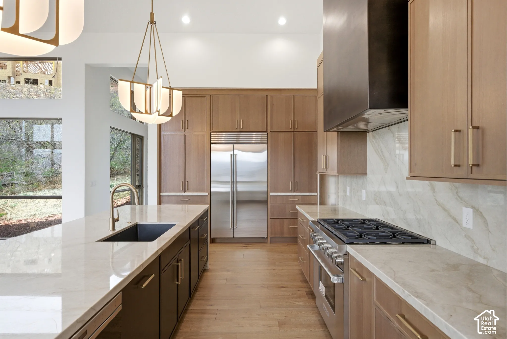 Contemporary kitchen featuring light wood-finish cabinetry, a large center island with an undermount sink, and light-toned countertops
