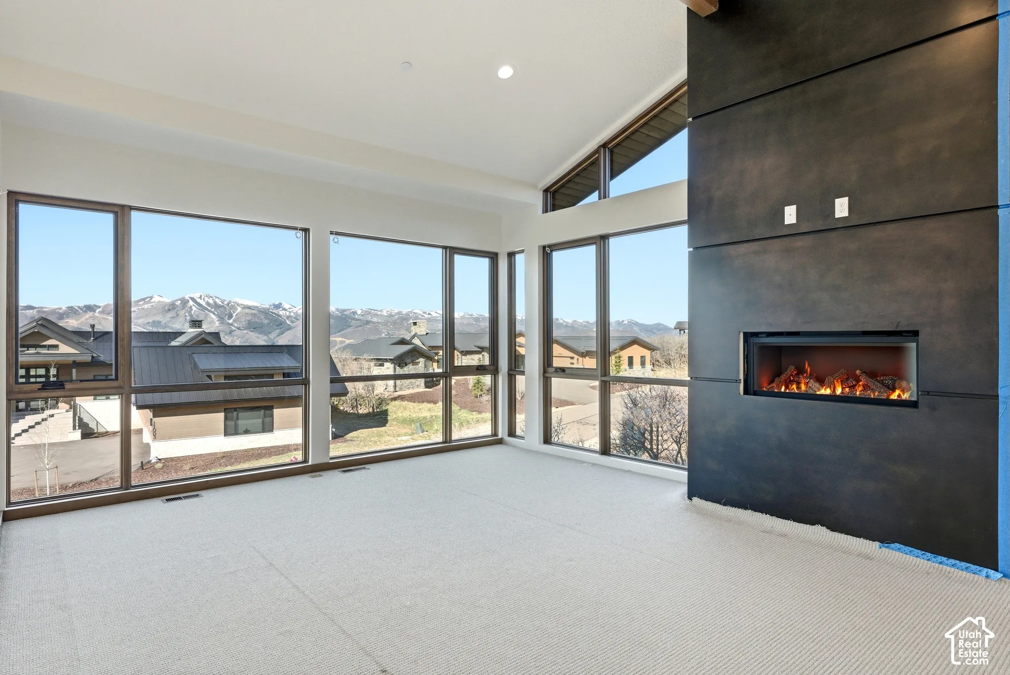 Unfurnished sunroom with vaulted ceiling, a residential view, and a mountain view