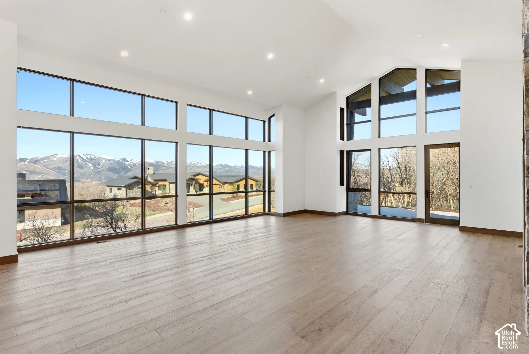 Unfurnished living room with a high ceiling, light wood finished floors, recessed lighting, and a mountain view