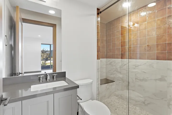 Bathroom with a marble finish shower, vanity, and recessed lighting