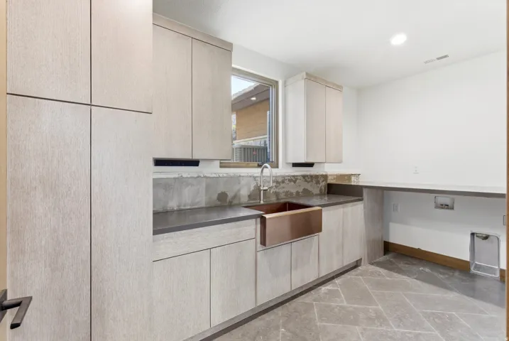 Kitchen featuring light wood finish cabinets, modern cabinets, recessed lighting, and dark countertops