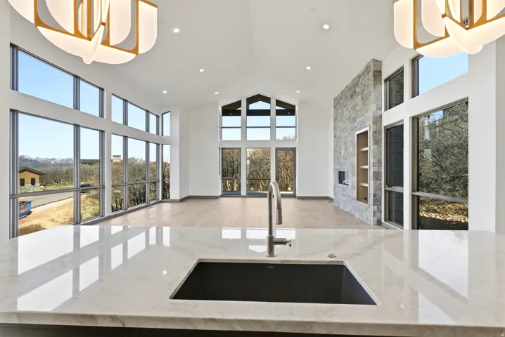 Kitchen featuring pendant lighting, light stone counters, a high ceiling, open floor plan, and light wood-style floors
