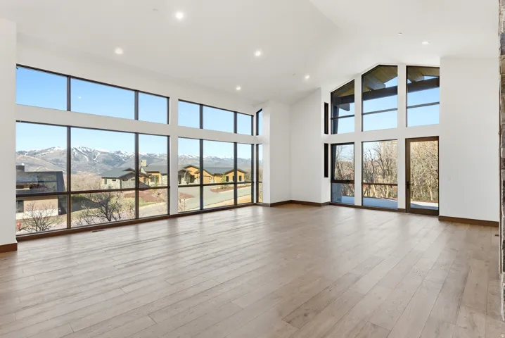 Unfurnished living room with a high ceiling, light wood finished floors, recessed lighting, and a mountain view