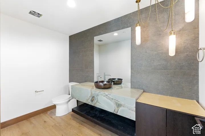 Bathroom featuring vanity, light wood-style floors, and tile walls