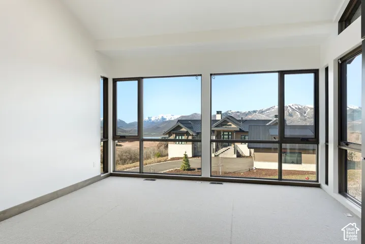 Unfurnished room with a mountain view, carpet flooring, and vaulted ceiling