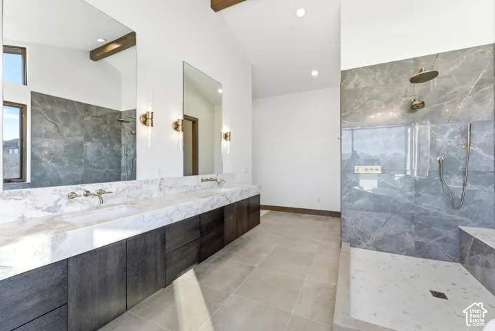 Full bath with a marble finish shower, double vanity, beam ceiling, and light tile patterned flooring