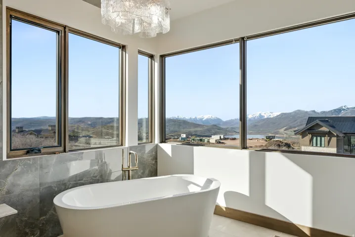 Full bath with a mountain view, a soaking tub, a chandelier, and tile walls
