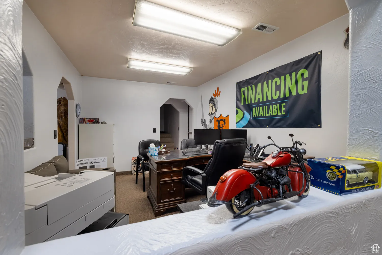 Bedroom with arched walkways, carpet floors, and an office area