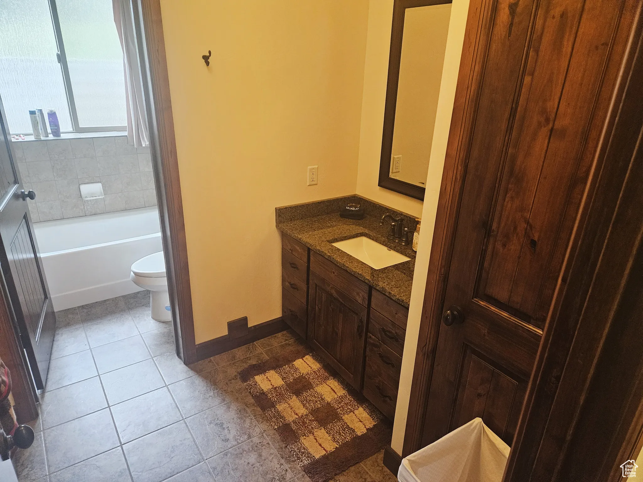 This split bathroom design features a separate vanity area, allowing for simultaneous use of the sink and the private toilet/tub room—ideal for shared or family use.