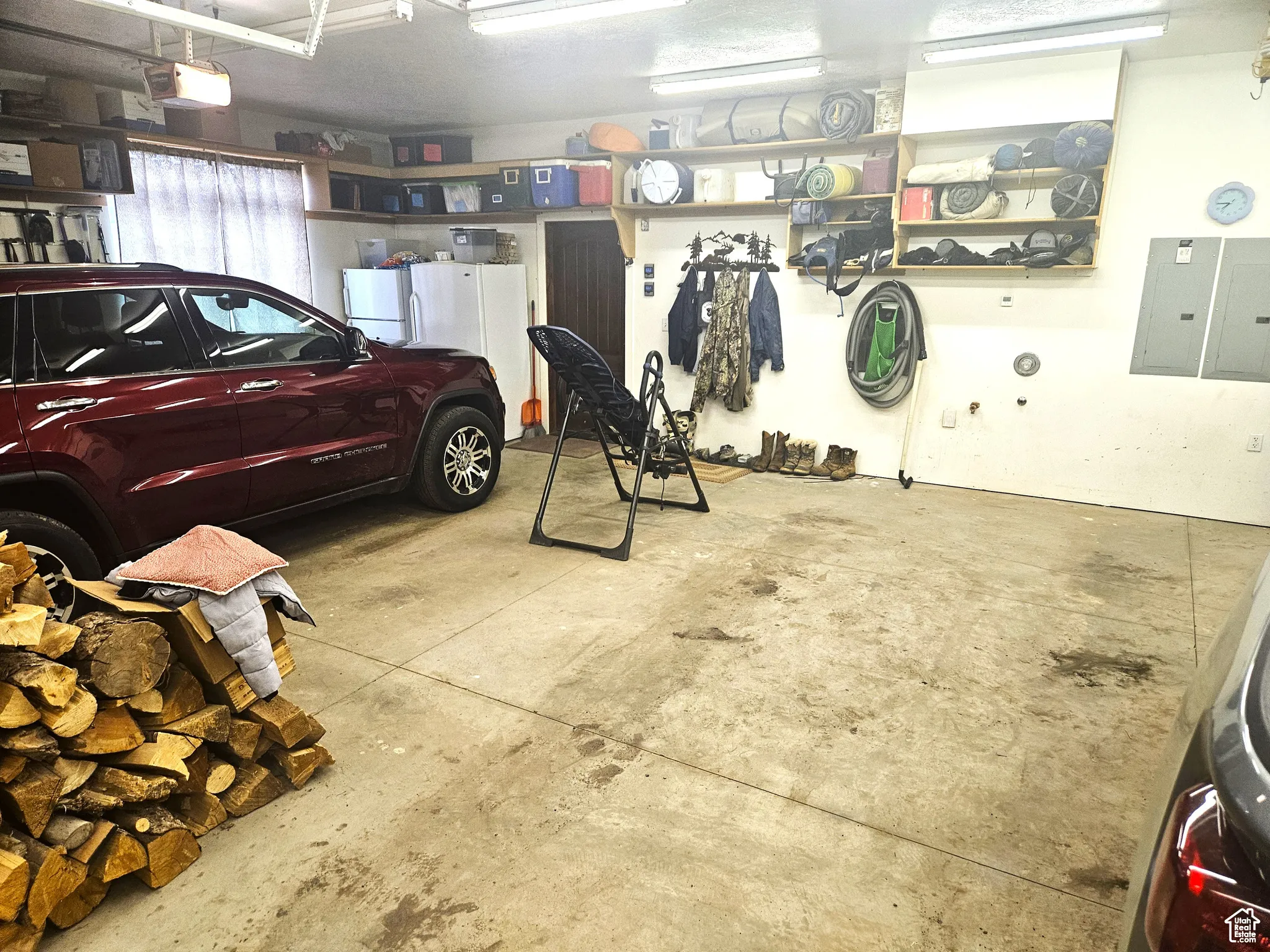 Garage featuring electric panel, freestanding refrigerator, and a garage door opener