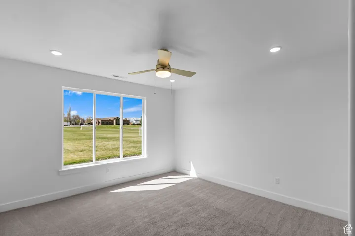 Carpeted empty room featuring a ceiling fan and recessed lighting