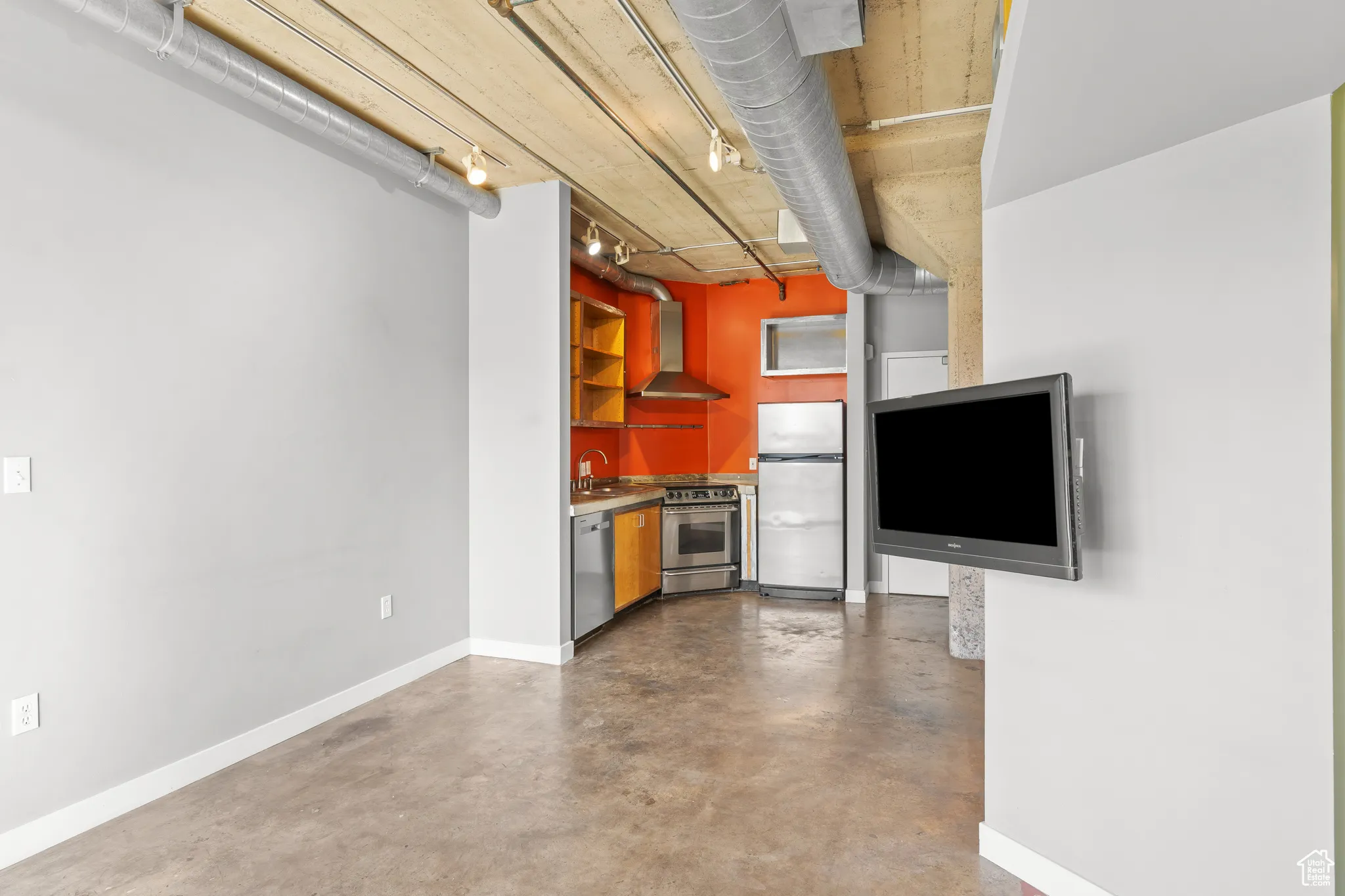 Kitchen with finished concrete floors, stainless steel appliances, wall chimney range hood, and open shelves