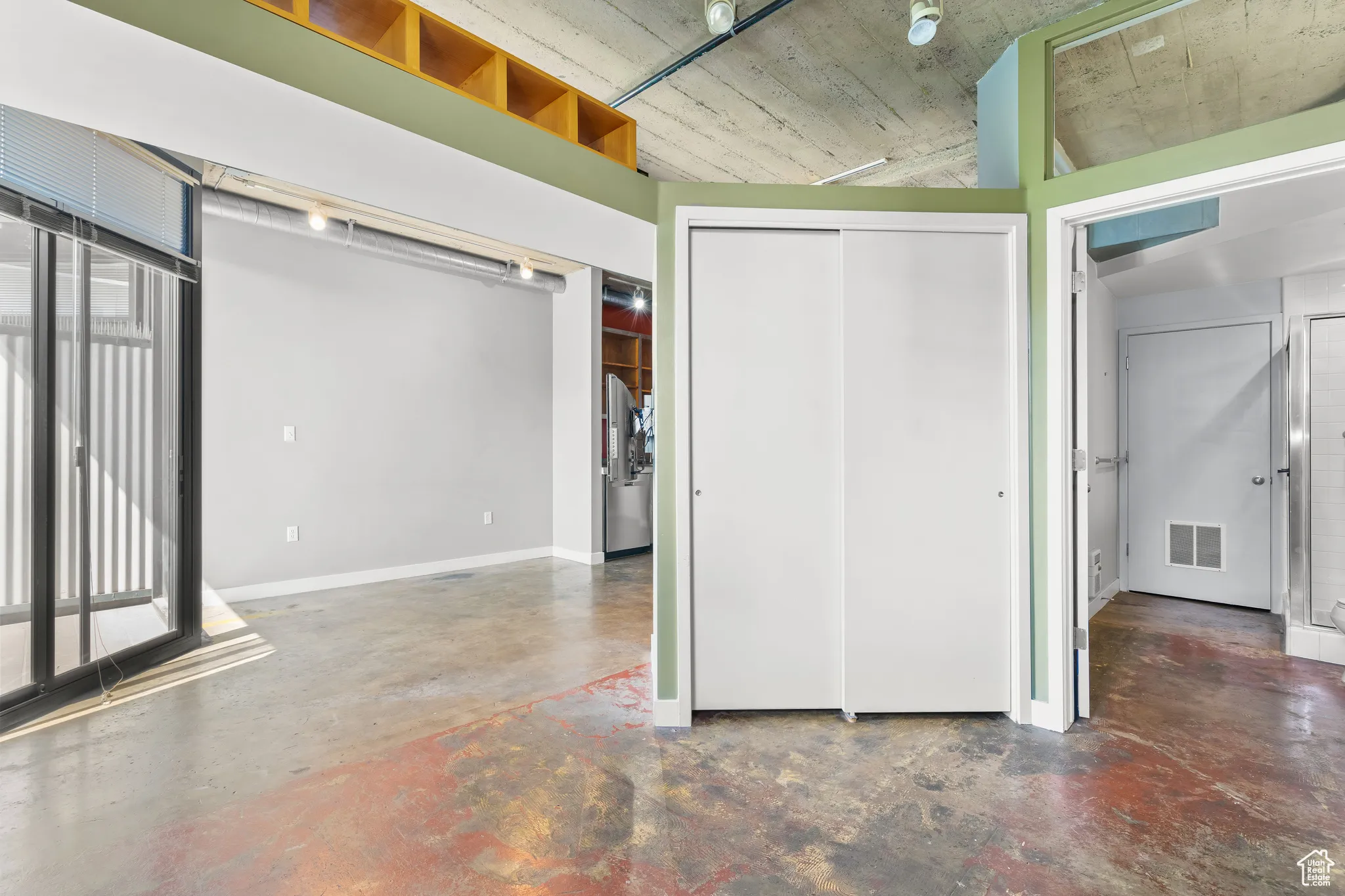 Unfurnished bedroom featuring finished concrete flooring, a closet, access to balcony