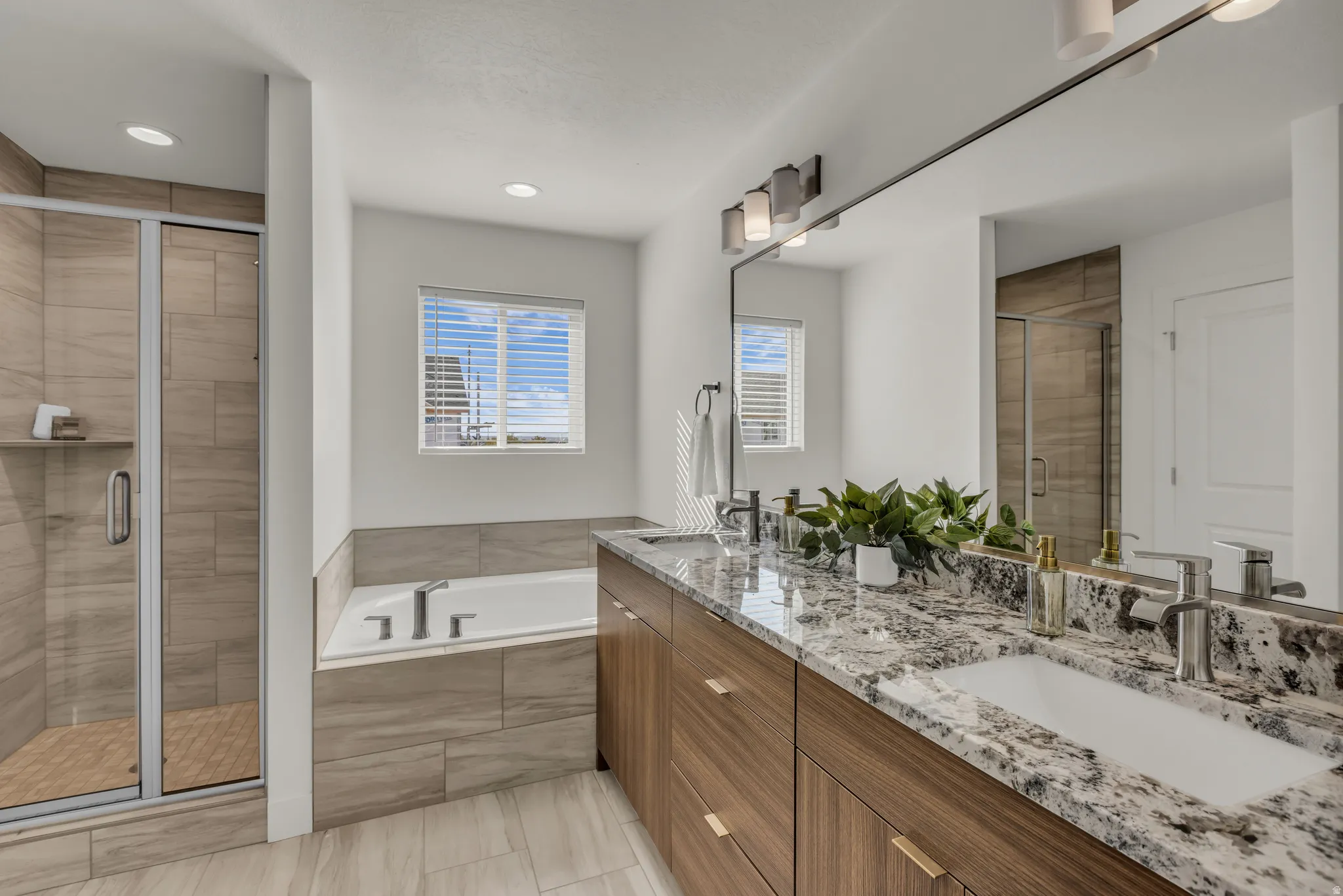 Full bath with double vanity, a shower stall, and a bath