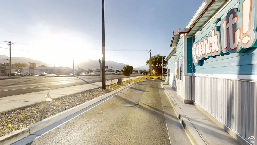 View of asphalt road featuring a mountain view, sidewalks, and curbs