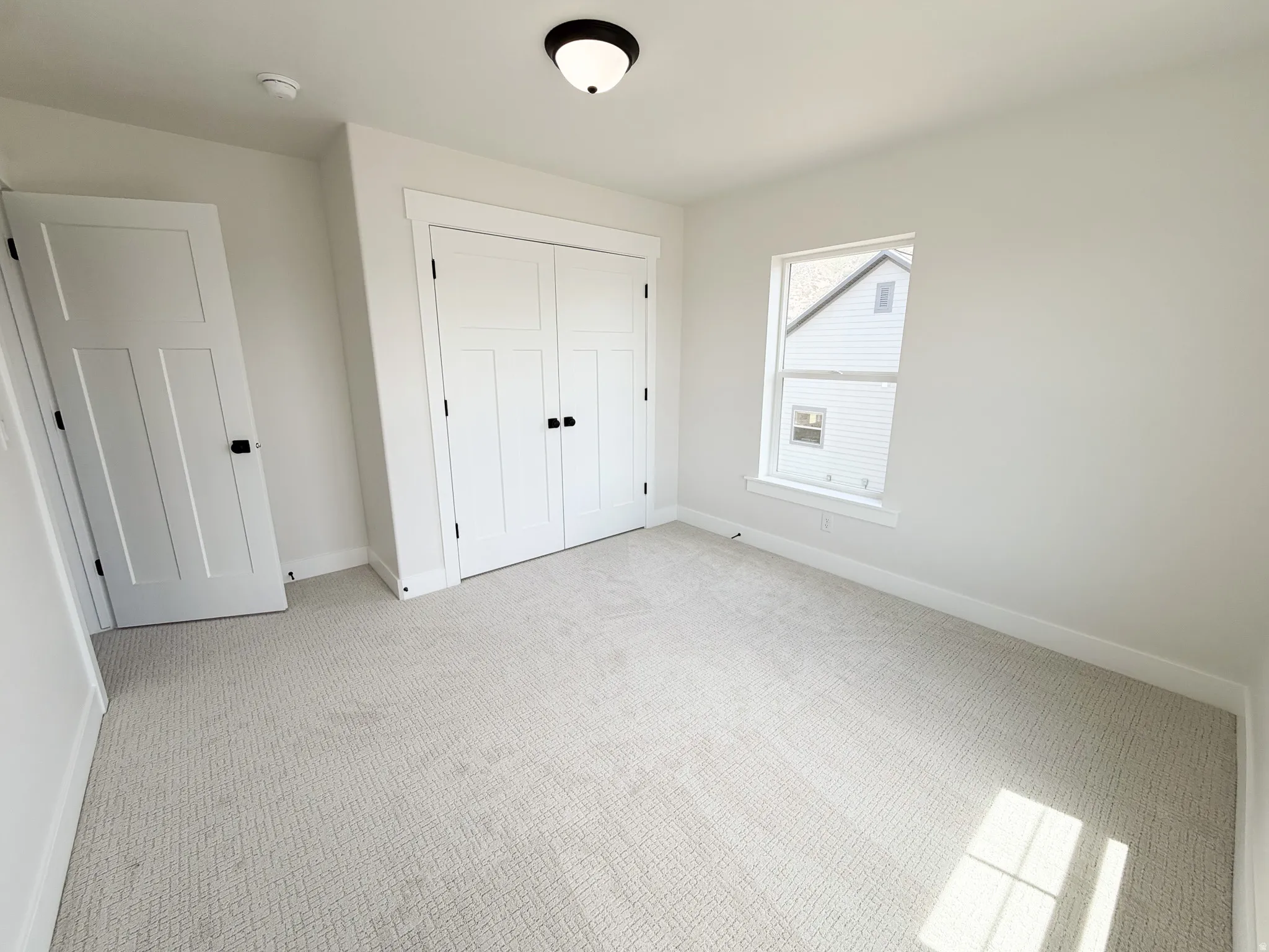 Neutral tone carpeting complemented by white walls, a white trim package, and a flush mount ceiling light fixture