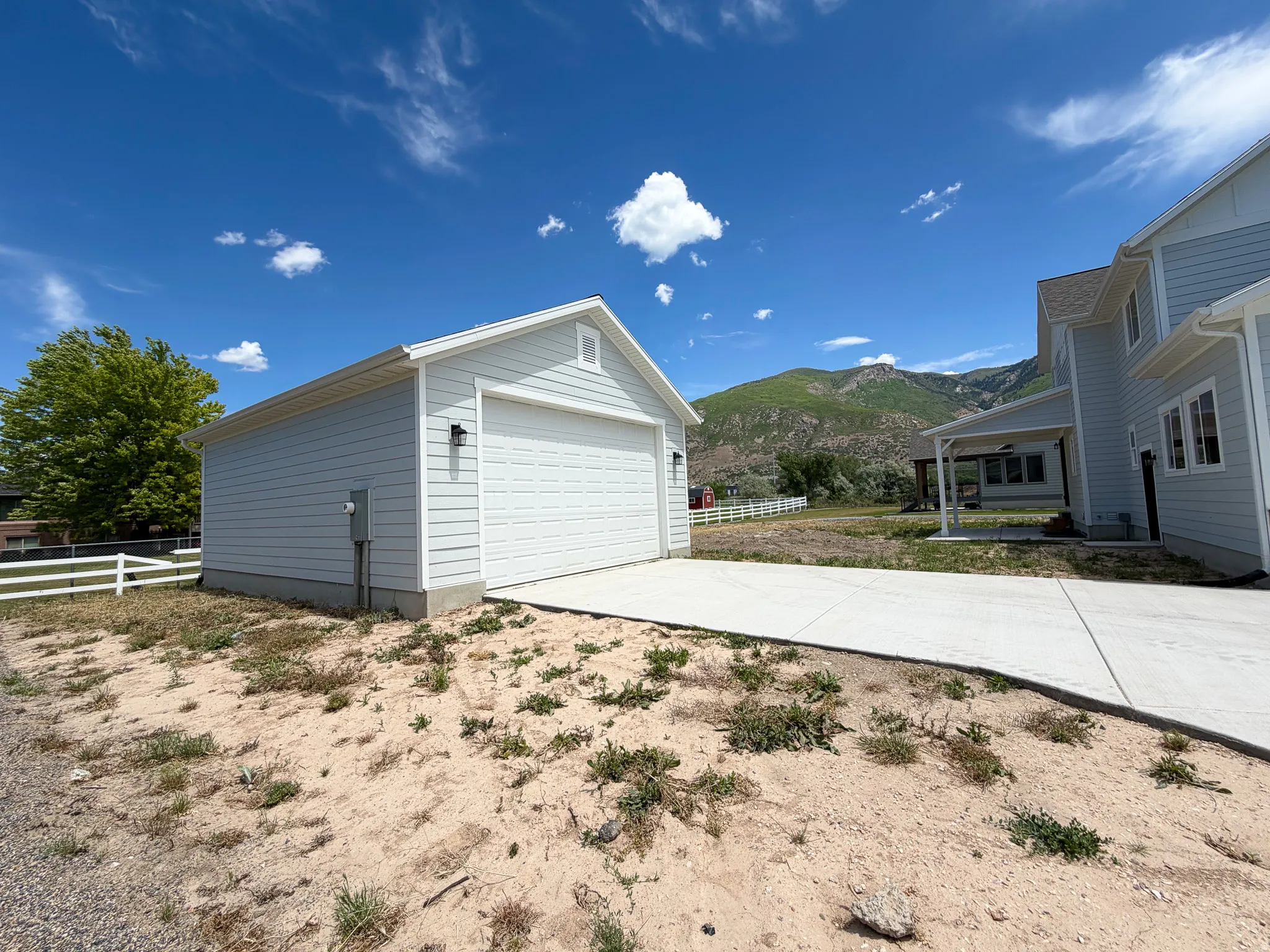 Detached single-car garage featuring light-toned horizontal siding, white trim, and a white panel garage door