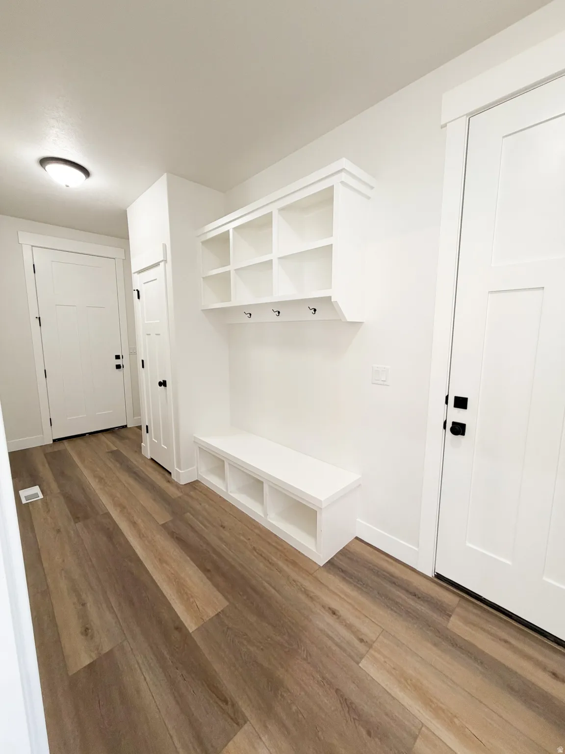 Entryway featuring a built-in bench with integrated shelving, overhead cubbies, and coat hooks