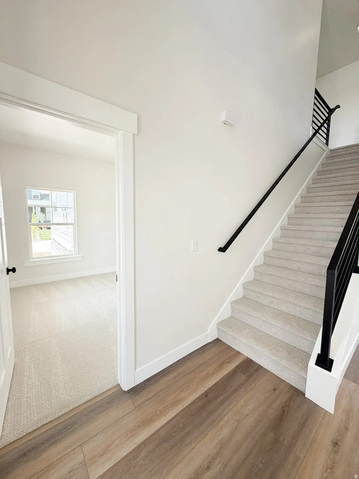 Staircase featuring black metal railings and light-toned carpeted treads