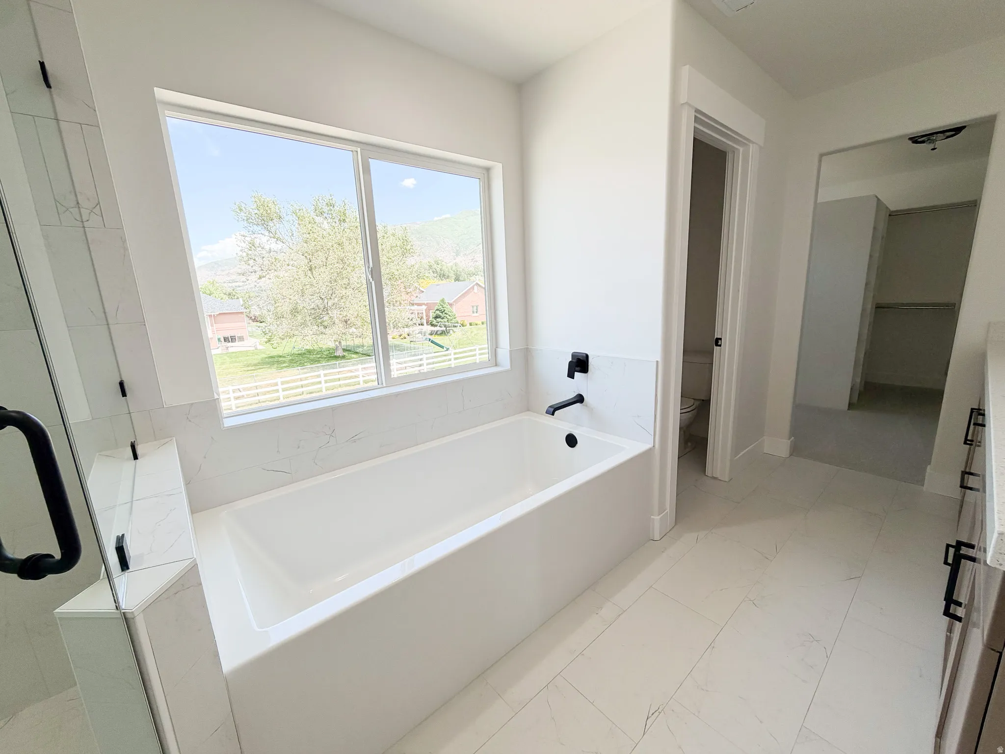 Soaking tub with black matte fixtures, set against a large window