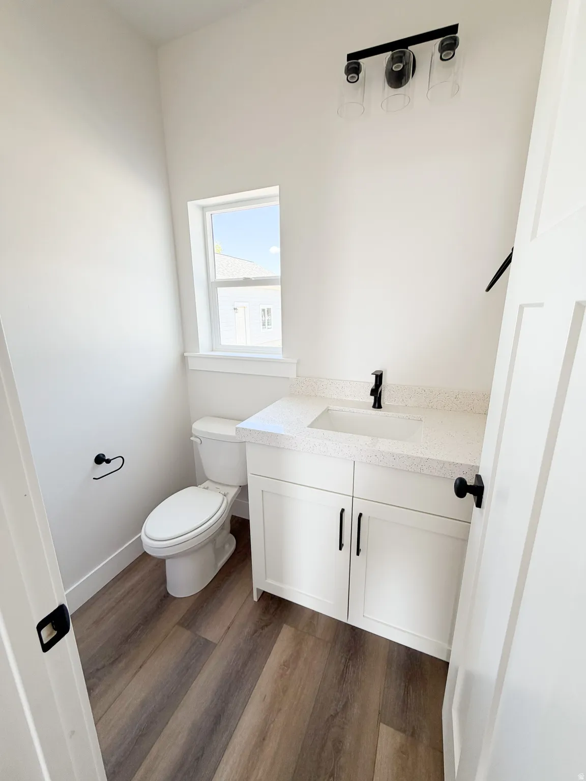 Powder room featuring a white single vanity with a solid surface countertop, undermount sink, and matte black faucet
