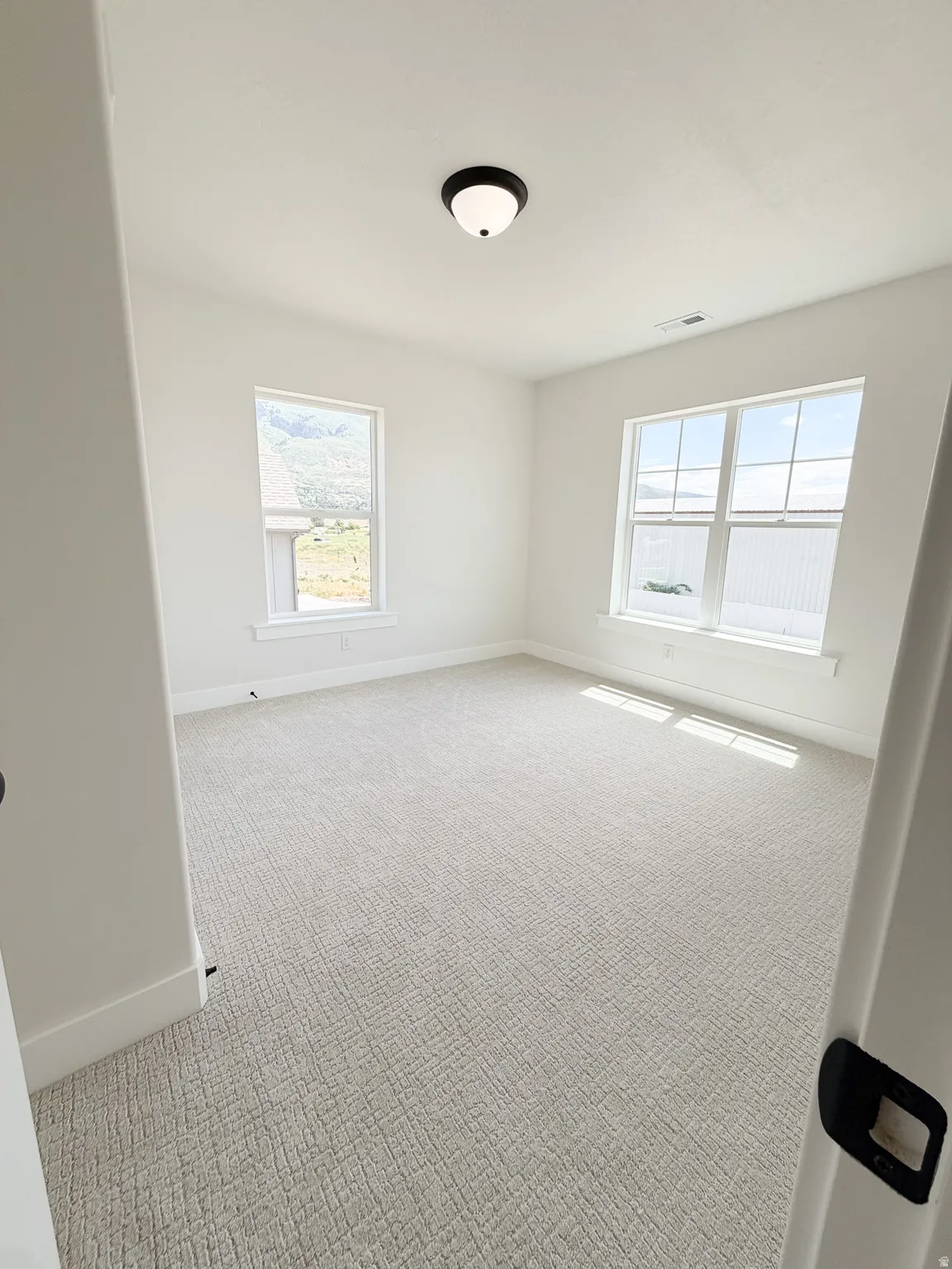 Spacious room featuring light-toned patterned carpeting and white walls