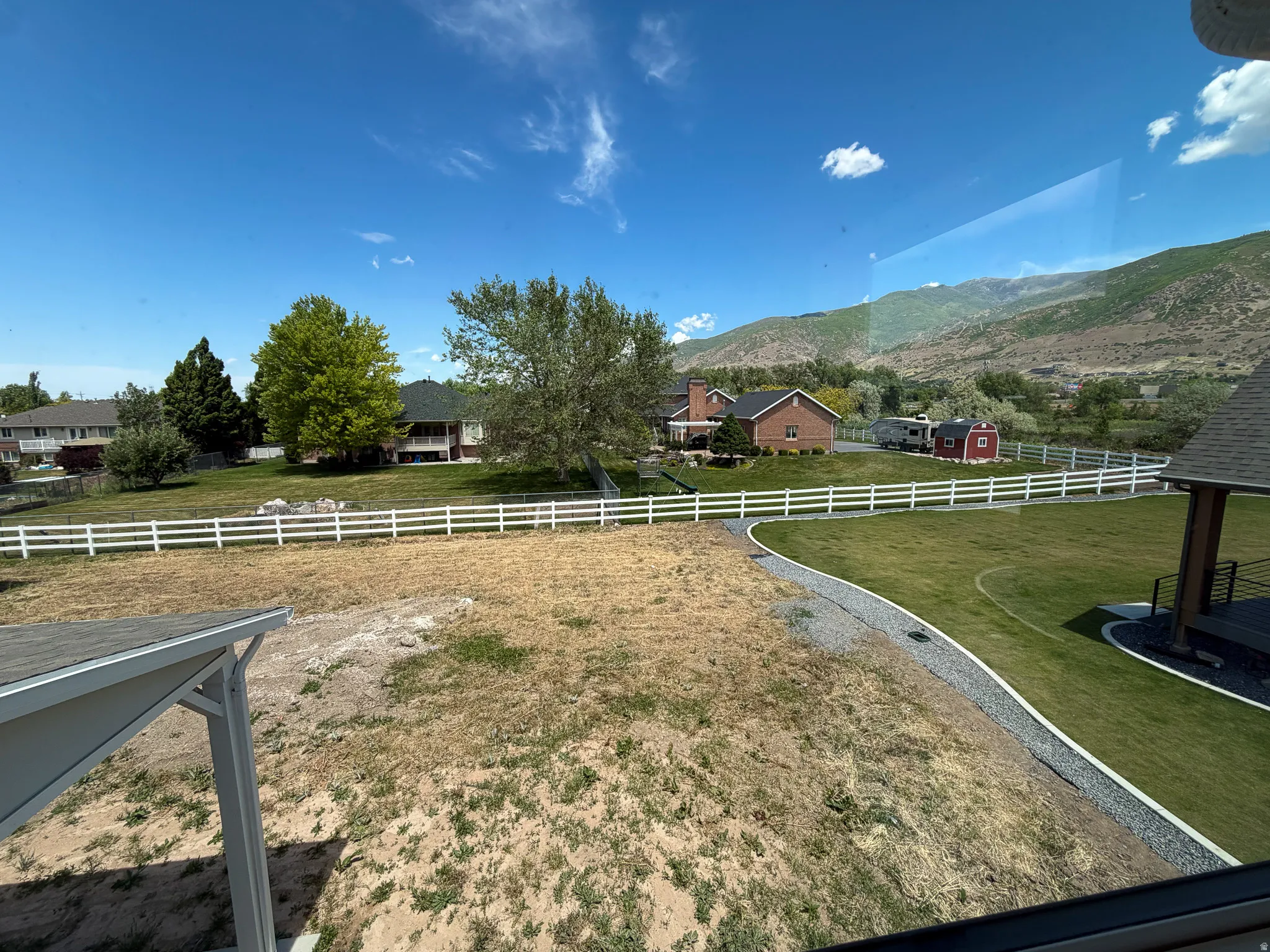 Expansive property featuring a green lawn, gravel-edged walkway, and a white picket fence