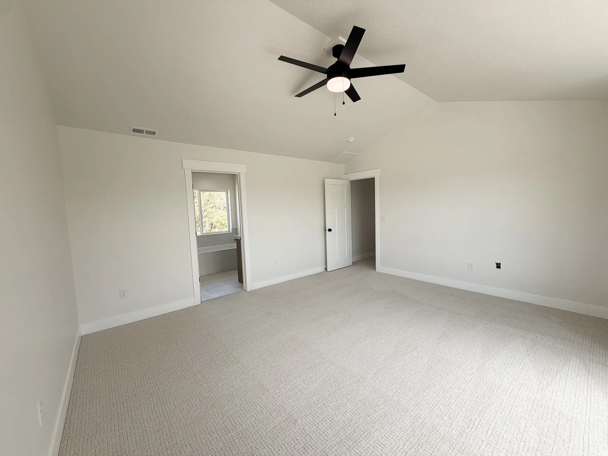 Spacious room featuring vaulted ceilings, a contemporary ceiling fan, and light-colored carpeting