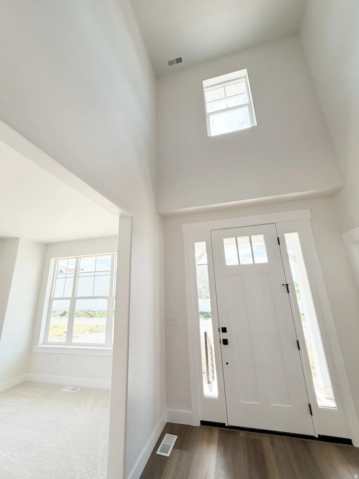 Two-story foyer with a transom window and a contemporary white front door with sidelights
