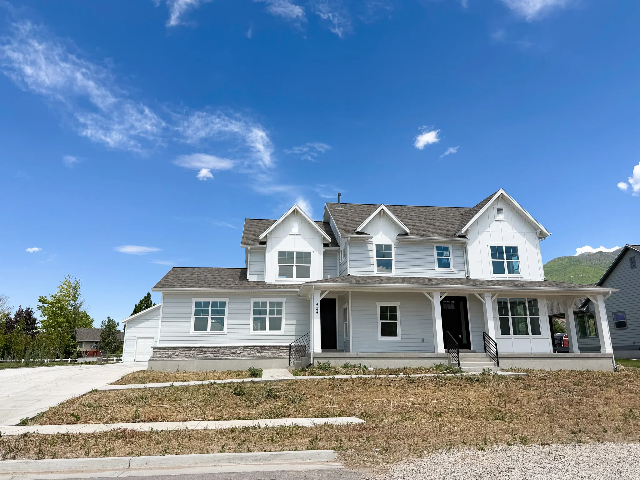 Two-story residence featuring light gray siding, a covered front porch with white columns, and a dark shingle roof