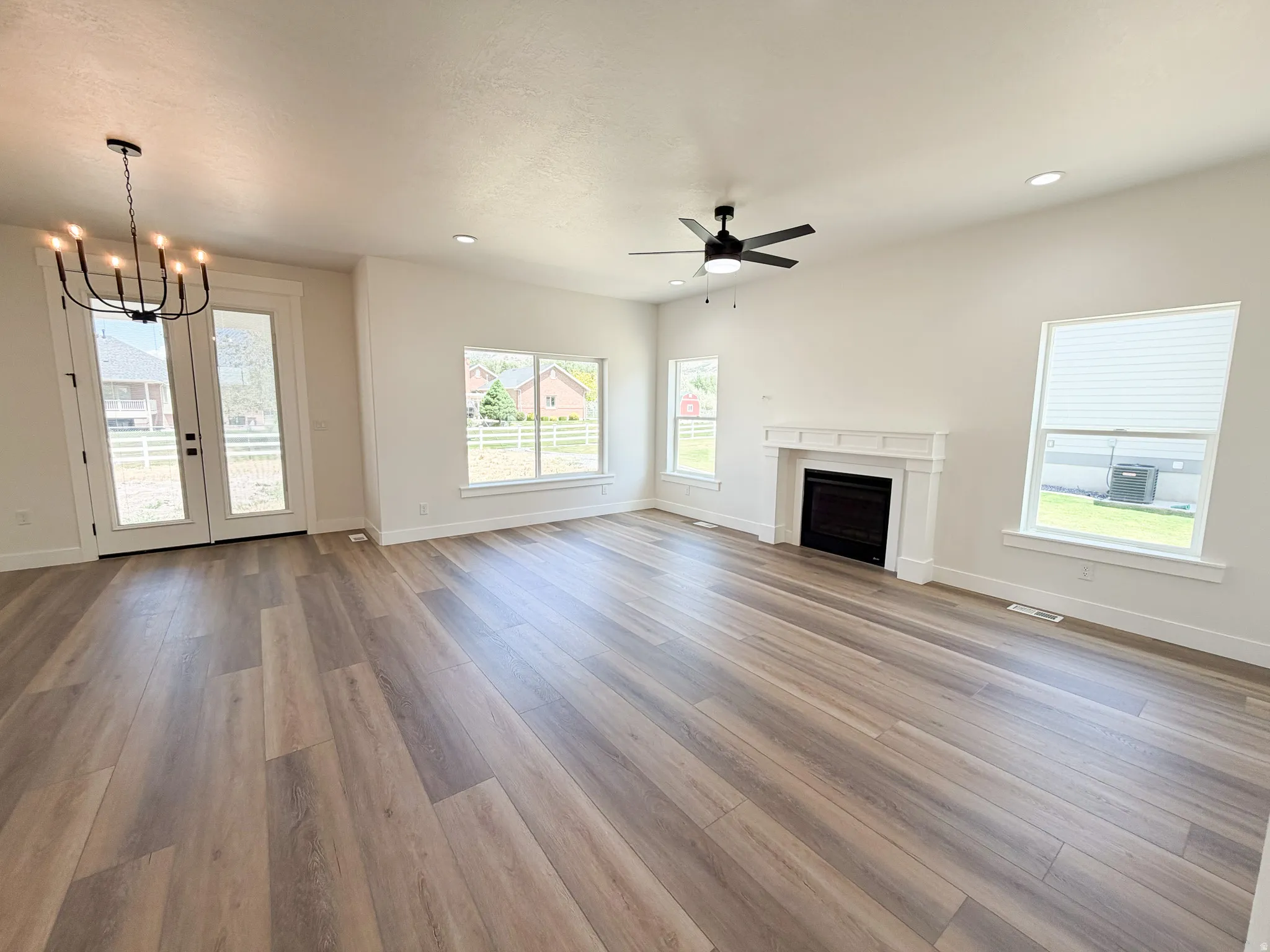 Spacious living area featuring wood-finish flooring, a white mantel fireplace, and recessed lighting