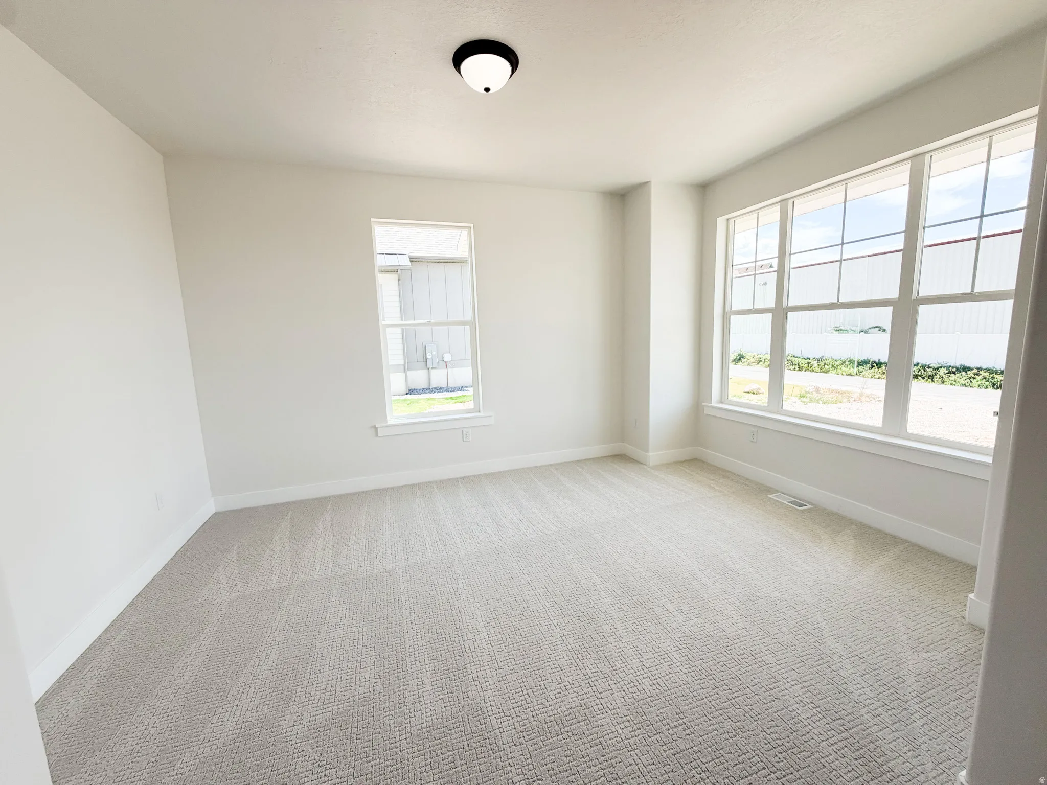 Spacious room with light-colored patterned carpeting, white walls, and white baseboards