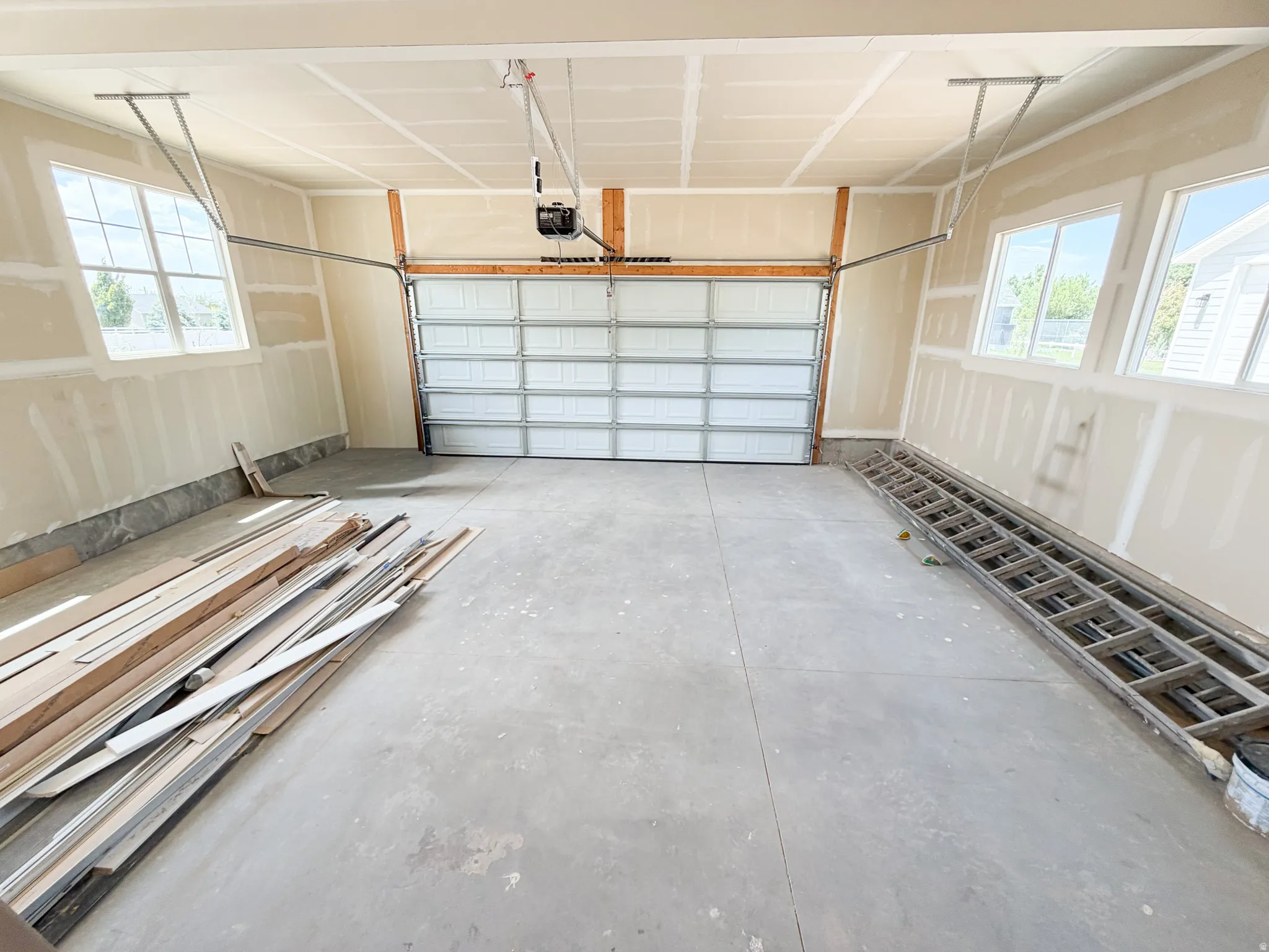 Spacious garage featuring a concrete floor, two windows, and an overhead garage door with opener