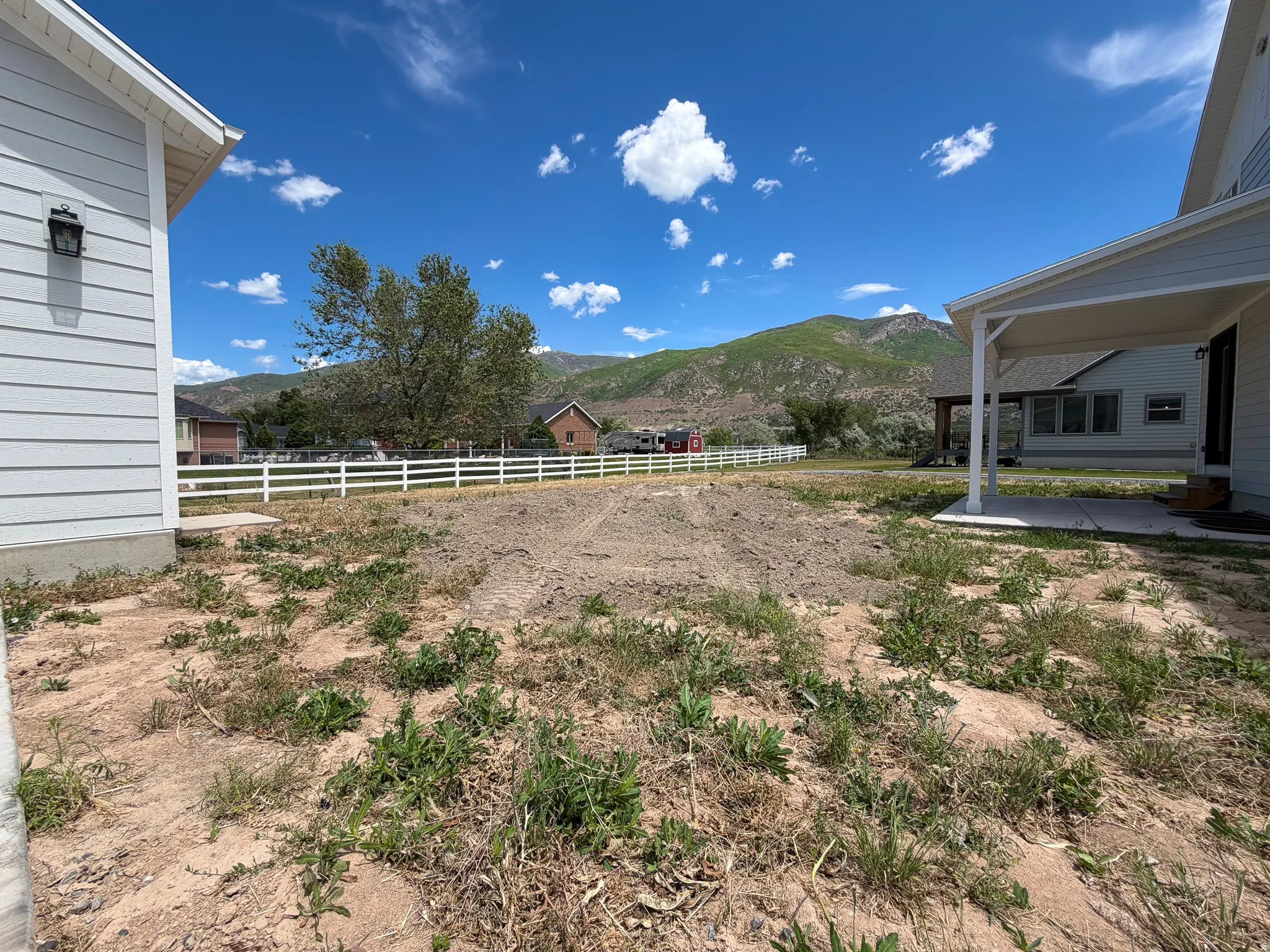 Expansive lot featuring mountain scenery and a white three-rail fence