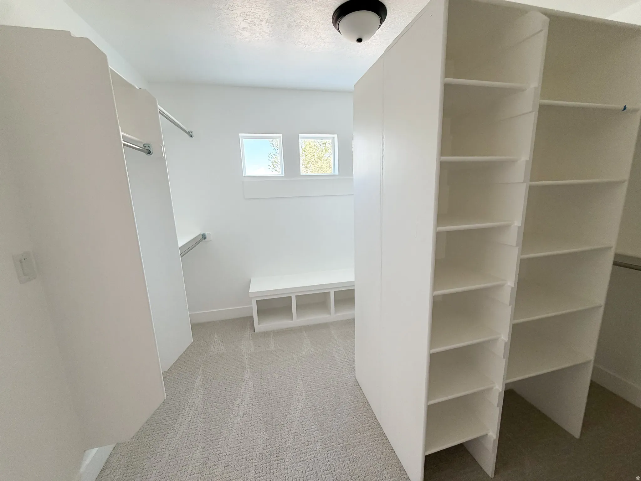 Custom walk-in closet featuring built-in shelving, hanging rods, and a storage bench