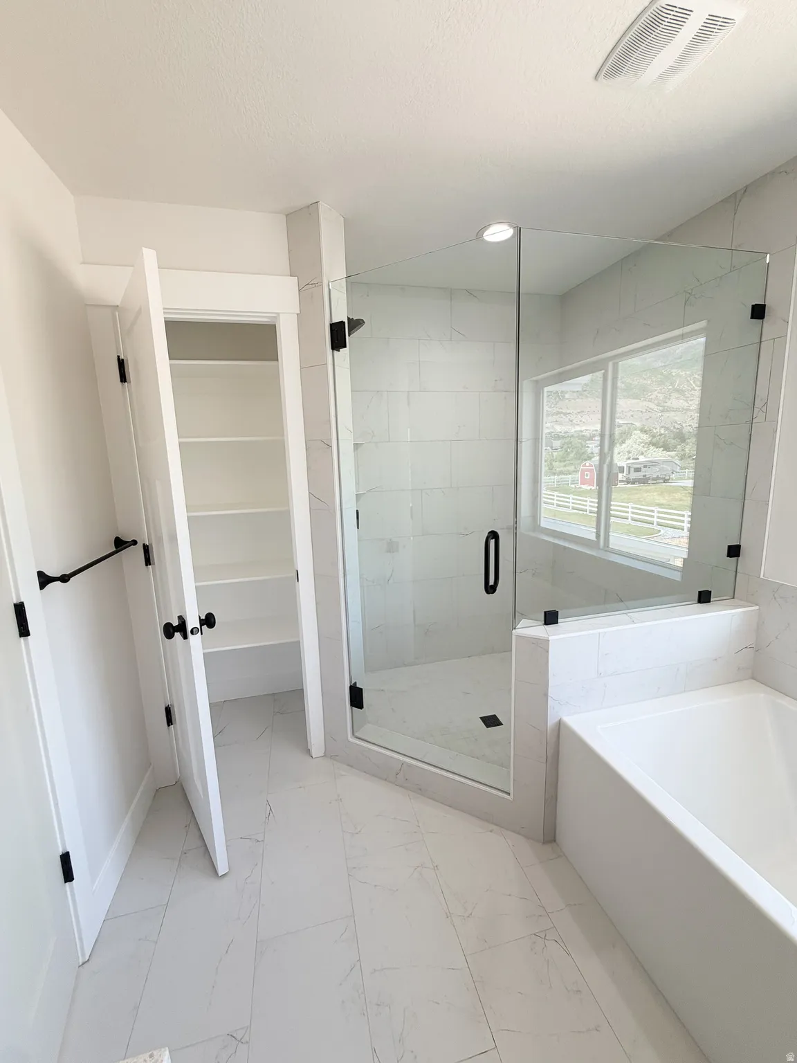 Modern bathroom featuring a glass-enclosed shower with tile surround, a built-in bathtub, and a separate linen closet with shelving